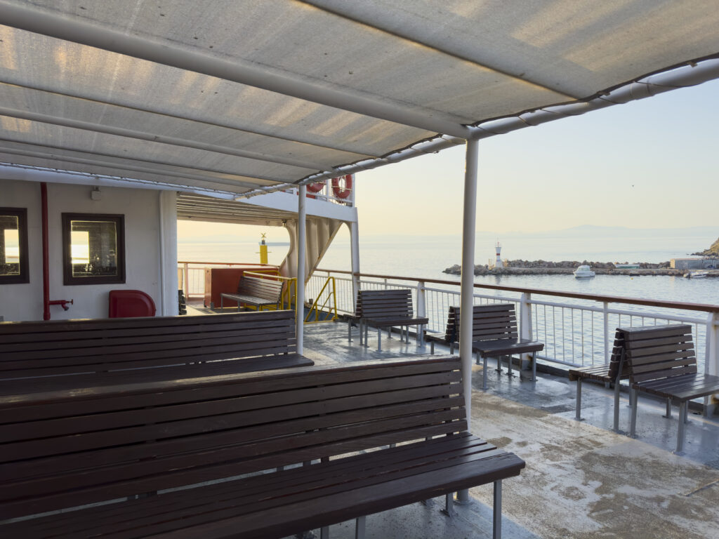 Sunny summer morning, the empty car and passenger ferry leaves the port of Bozcaada. No people. A Turkish island in the North Aegean Sea